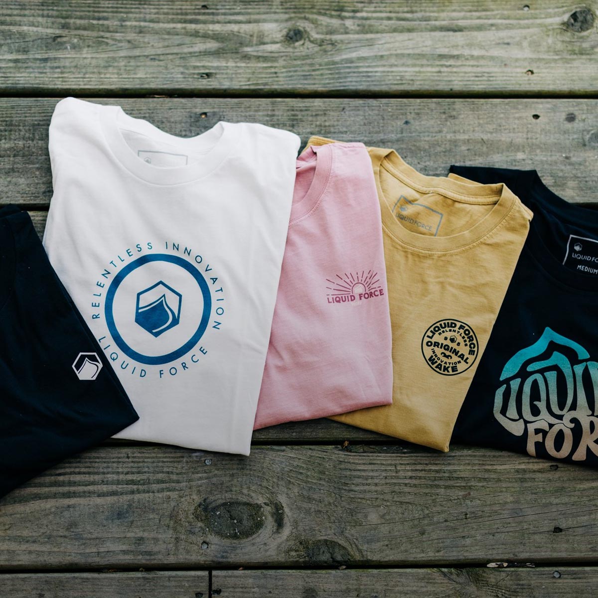 Liquid Force Apparel Collection - Close up picture of various LF T-Shrits folded up next to one another displaying their graphics