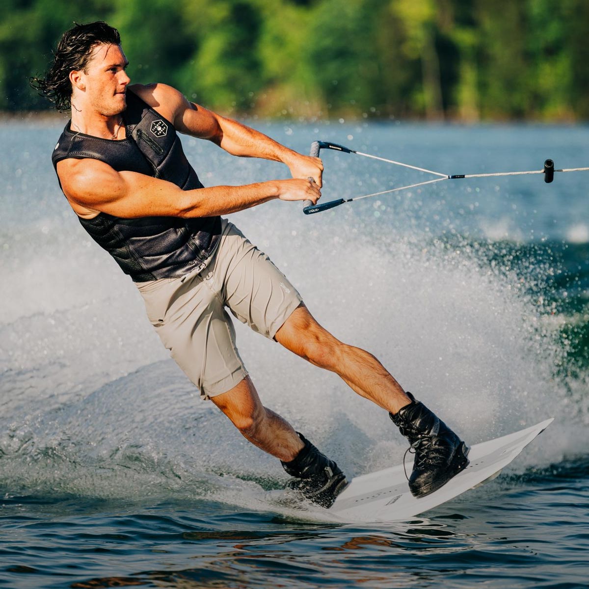 Liquid Force Vest Collection - Closeup shot of LF Athlete Fynn Bullock carving out into the flats on a wakeboard behind a boat wearing a LF Vest.